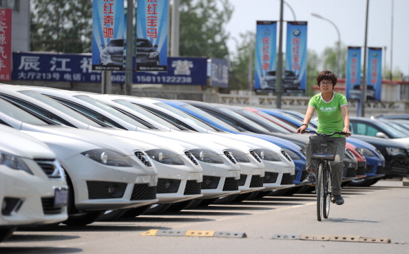 A woman rides a bicycle past a row of ne