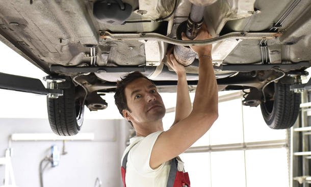 Car mechanic working in repair garage checking underbody of a car model released Symbolfoto propert
