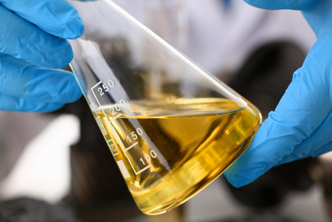 Male Hands In Protective Gloves Hold Test Tube In Hands Produces Chemistry Test Of Motor Oil Automat